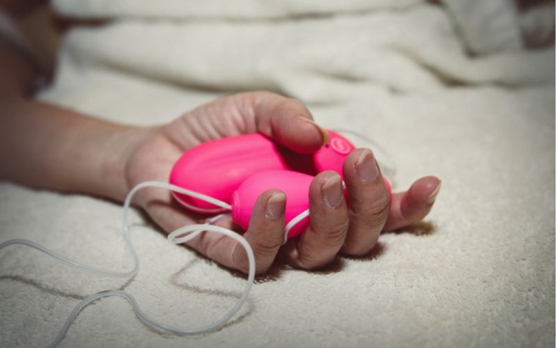Ružové vibračné vajíčko s ovládačom v ženskej ruke